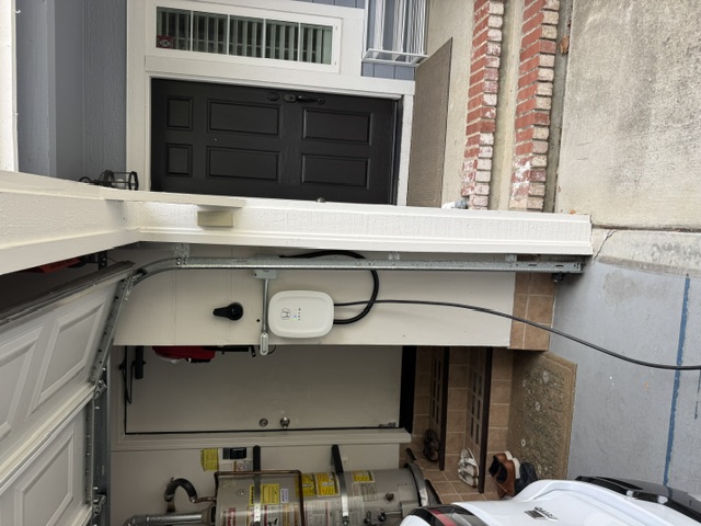 A white EV charger mounted inside a garage beside the door to the house