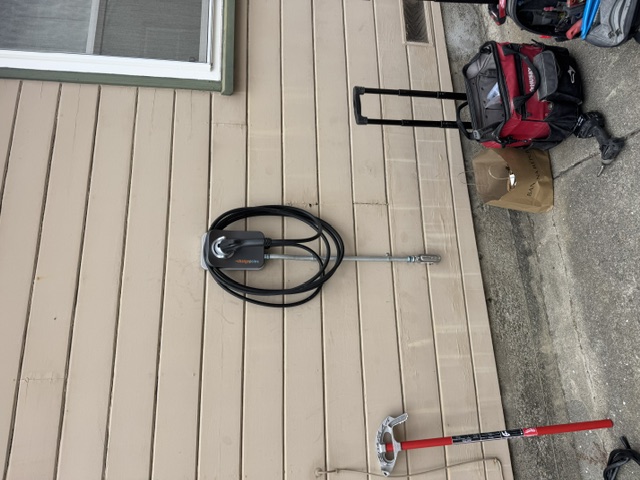 An EV charger installed on tan siding with a tool bag and tools beside it