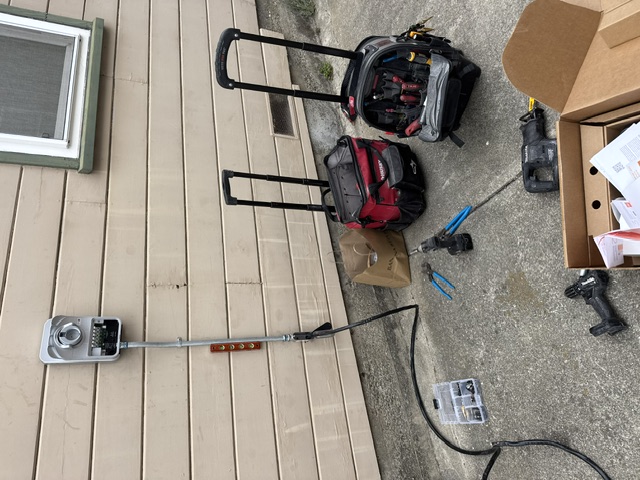 A new meter socket on lap siding with conduit, tool bags and boxes on the ground below